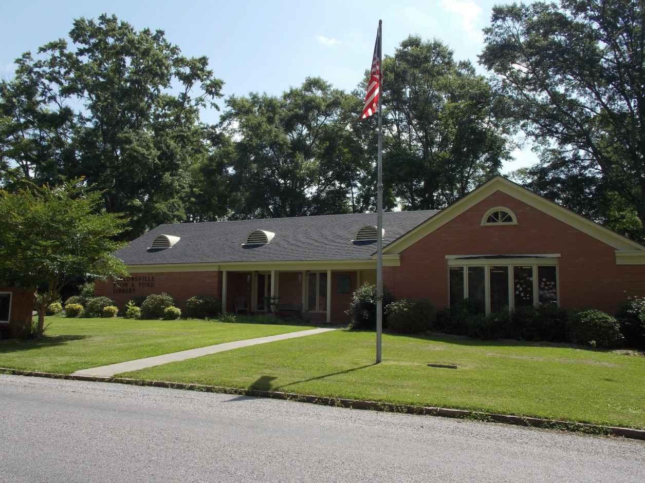 Evon A. Ford Library Building with brick exterior, gabled roof, and flagpole in front.