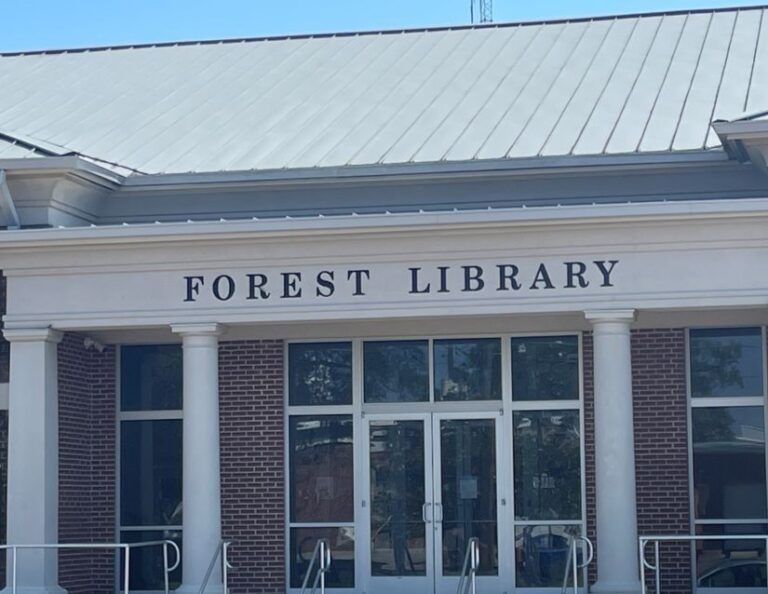 Entrance of Forest Library with brick facade, white columns, and glass doors.