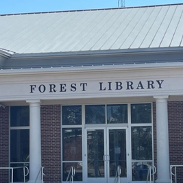 Entrance of Forest Library with brick facade, white columns, and glass doors.