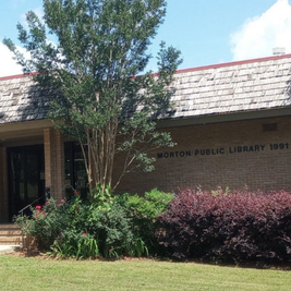 Morton Public Library with brick facade, shingled roof, and landscaped entrance.