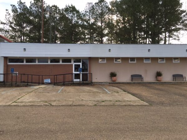 Puckett Public Library entrance with glass door, accessibility ramp, benches, and potted plants.