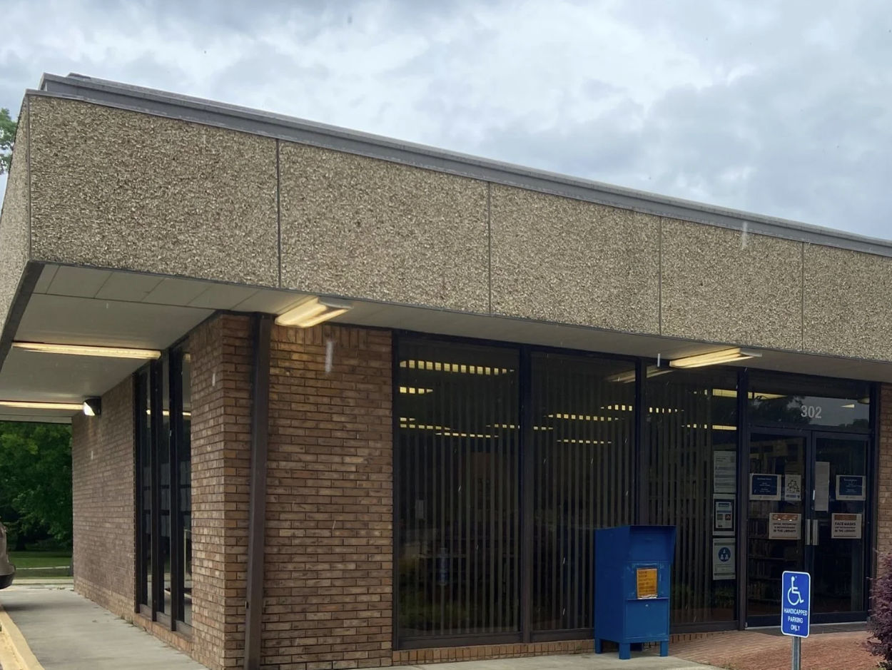 R.T. Prince Memorial Public Library with brick and concrete exterior, glass doors, and accessibility sign.