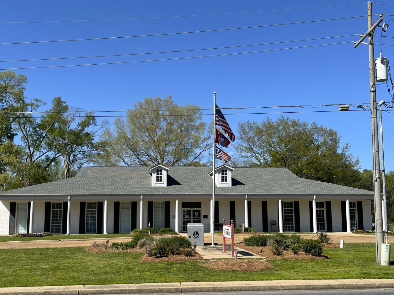 Exterior of Richland Public Library with white walls, columns, and three flags flying in front.