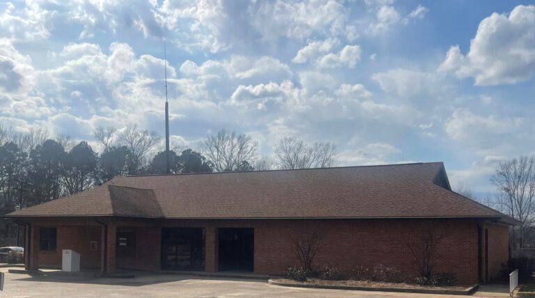 Sandhill Pisgah Library, surrounded by trees under a partly cloudy sky.