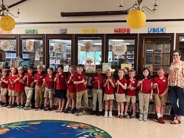 Children in matching red shirts and khaki bottoms standing in a line.