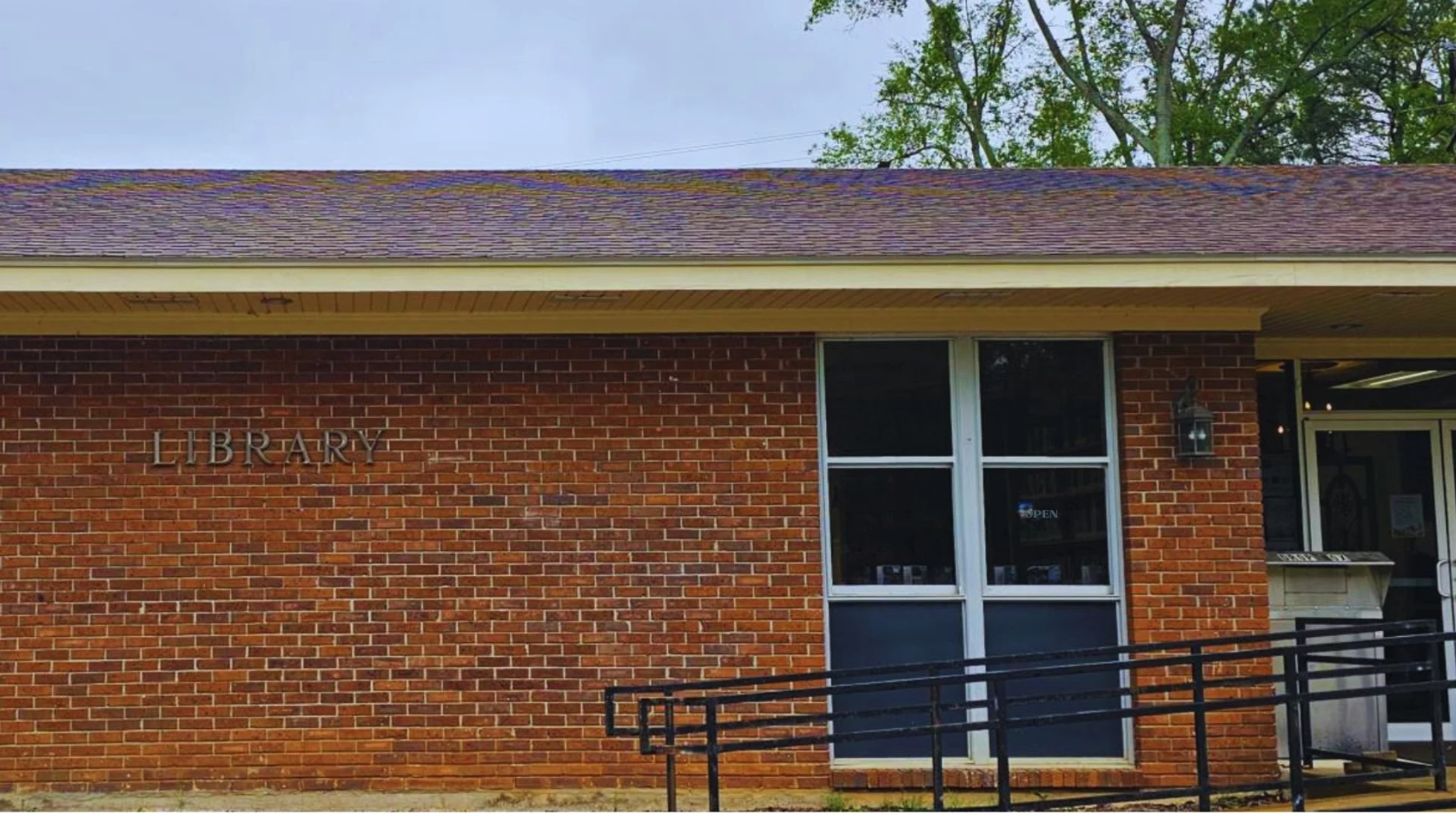 Sebastopol Public Library with red brick exterior, glass entrance, and event sign near walkway.